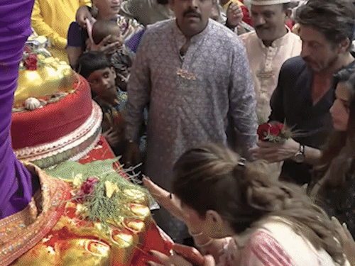 शाहरुख को उनकी मैनेजर पूजा ददलानी गणपति के चरण स्पर्श करने का तरीका सिखाती दिखीं।