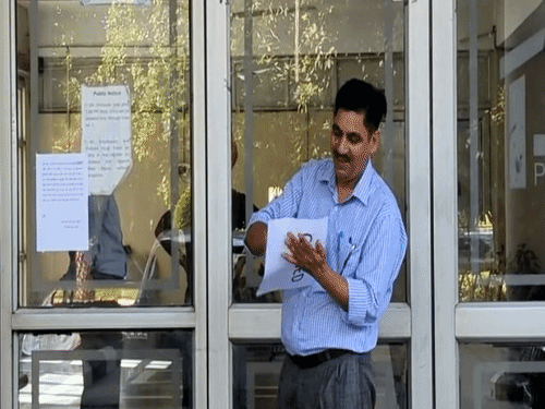 ईडी टीम के अधिकारी गमाडा बिल्डिंग के कई हिस्सों पर क्लोज्ड का पोस्टर लगाते हुए।