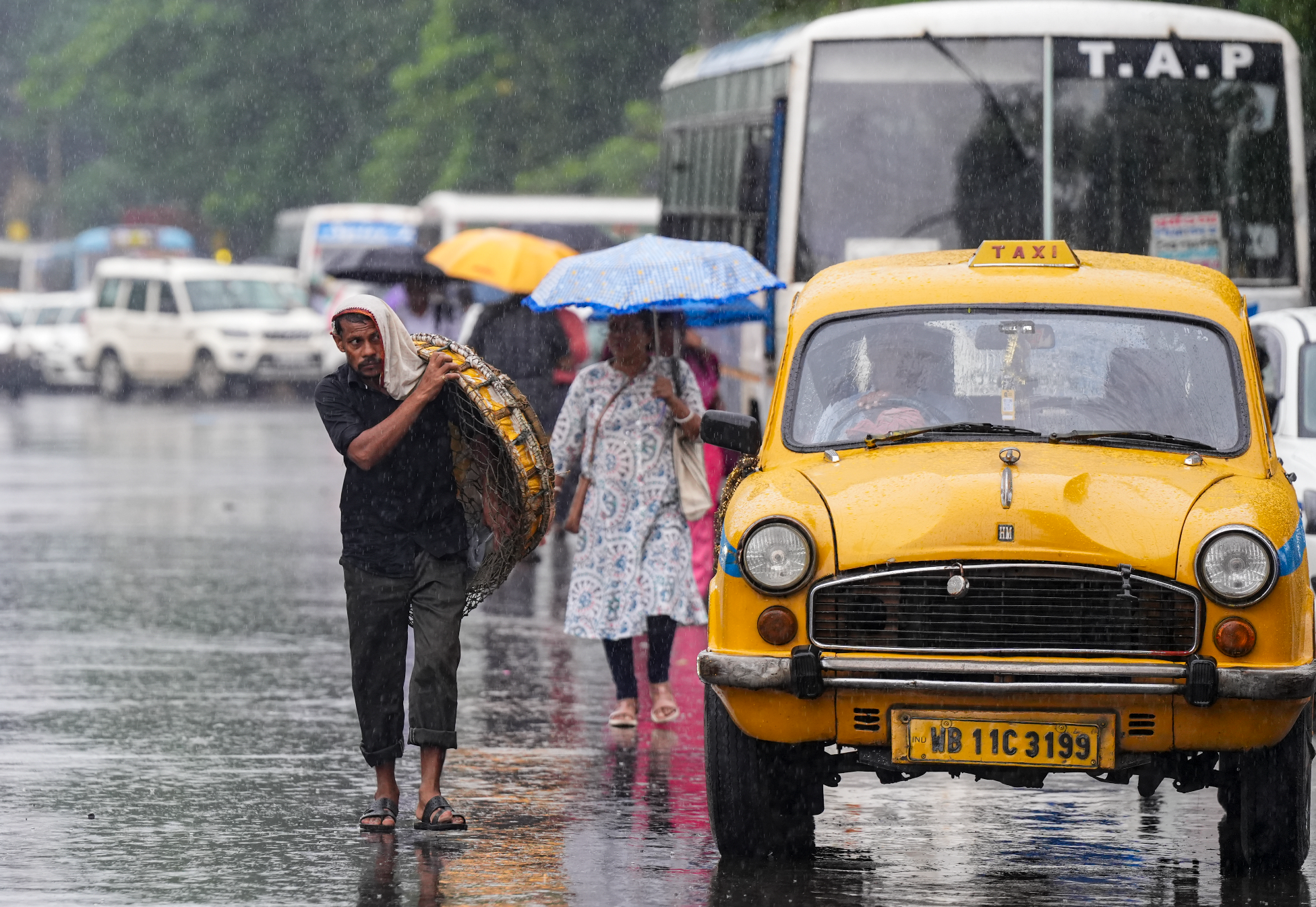 कोलकाता में बारिश के बीच सड़क पर जाते समय खुद को ढके हुए यात्री।