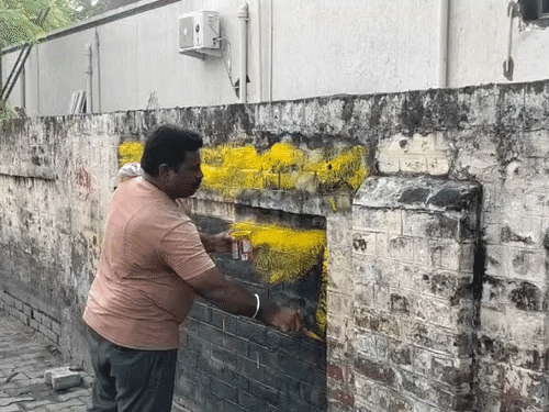 नारे लिखी गई जगह पर पेंट किया जा रहा है।