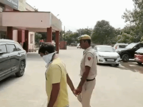 आरोपी को थाने ले जाता पुलिसकर्मी।