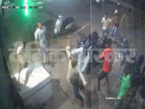 दुकानदार पर तेजधार हथियारों से हमला करते हुए और पीछे एक युवक द्वारा ईंट फैंकी जा रही है