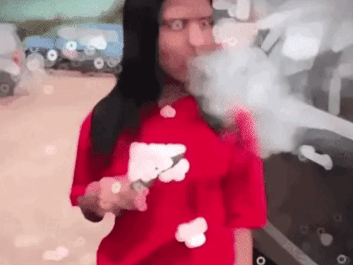 हाथ में सिगरेट लेकर धुआं उड़ा रही युवती, दूसरे हाथ में चाकू ली हुई है।
