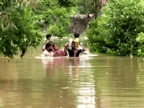 छत्तीसगढ़ के रायपुर की खारुन नदी में आई बाढ़ के बीच बच्चों को कंधे पर उठाकर निकलता परिवार।