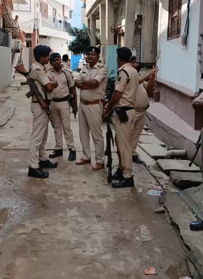 रेड के दौरान घर के बाहर खड़ी पुलिस की टीम।