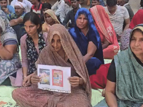 आश्रम के बाहर परिजनों के साथ गांव की महिलाएं और पुरूष धरने पर बैठे हैं।