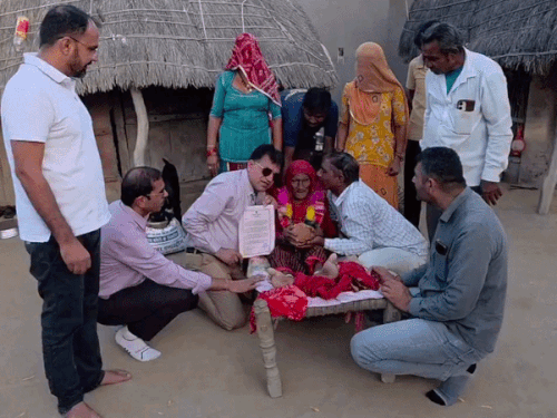 बालोतरा के धोरीमन्ना में 101 साल की वोटर हेमी देवी को सर्टिफिकेट देकर बात करते एसडीएम बद्रीनारायण विश्नोई (काले चश्मे में)।
