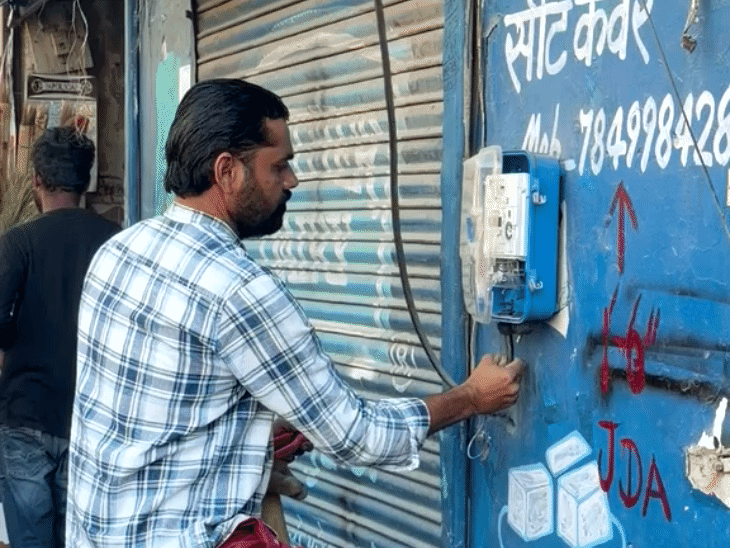 जेडीए की कार्रवाई से पहले दुकानों के बाहर से बिजली के कनेक्शन को हटाते लोग।
