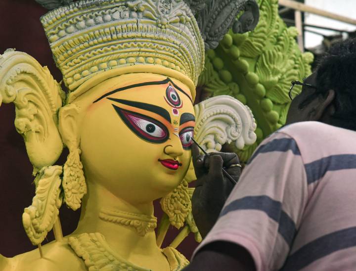 कोलकाता में चोख्खु दान परंपरा के तहत एक कारीगर दुर्गा मां की आंखों में रंग भर रहा है।
