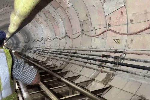 पटना मेट्रो के लिए बनाई गई सुरंग से गुजरते निर्माण कार्य से जुड़े लोग।