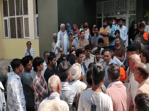 पोस्टमॉर्टम हाउस पर पुलिस से बातचीत करते मृतक युवक के परिजन।