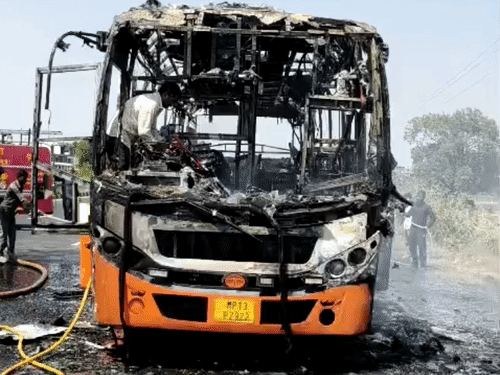 बस में लगी आग बुझाते हुए फायर कर्मचारी।