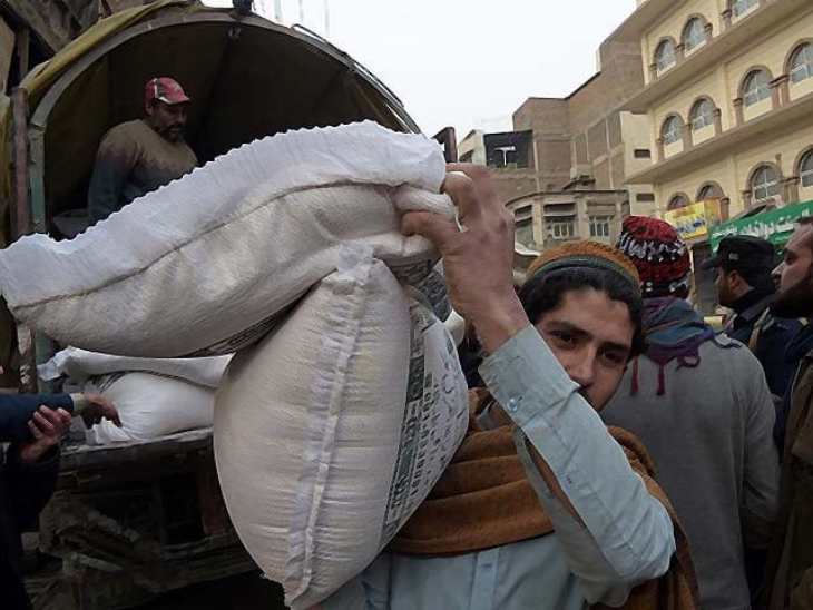कंधे पर गेहूं की बोरी ले जाते पाकिस्तानी शख्स की तस्वीर। (फाइल फोटो)
