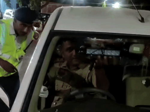 युवकों की कार की जांच करते ट्रैफिक पुलिस कर्मी।