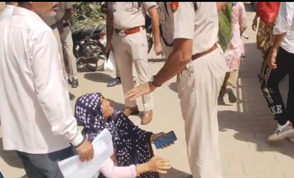 नारनौल में एसएसओ अनिल कमांडो के पैर पकड़ती महिला।