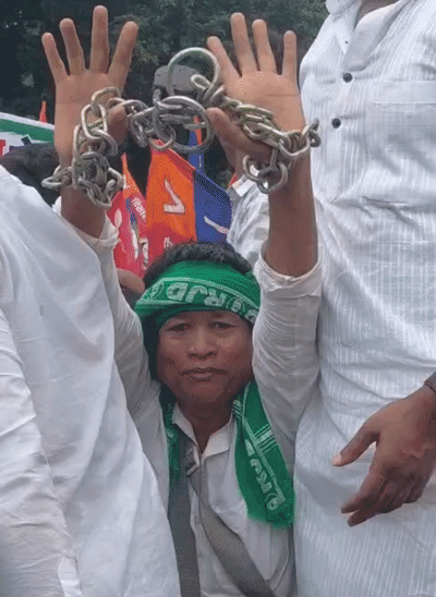 एक कार्यकर्ता हाथों में हथकड़ी लगाकर प्रदर्शन में शामिल हुआ।