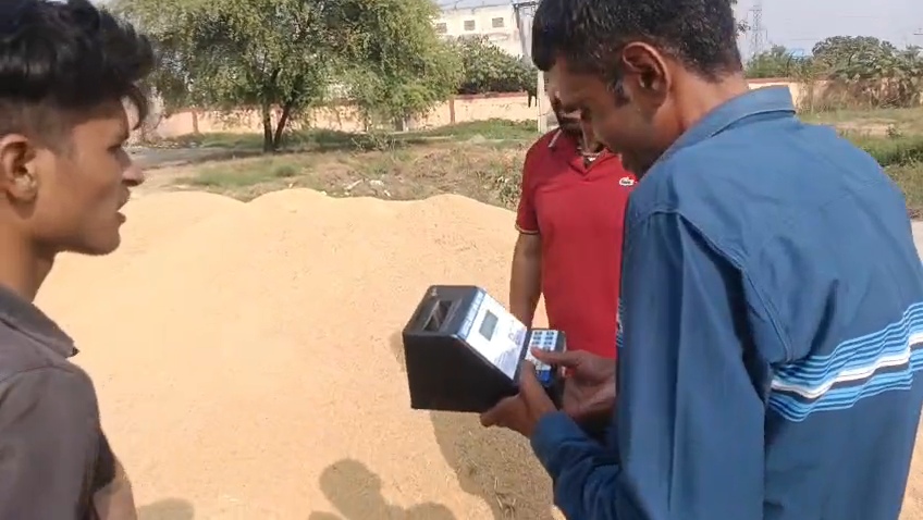 धान में नमी की जांच करवाते हुए किसान।