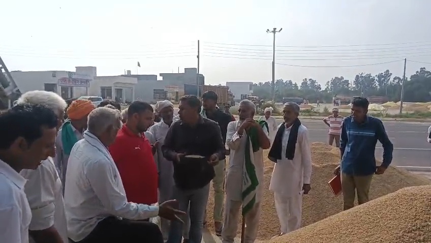 धान की सूखी ढ़ेरियों पर मौजूद किसान।