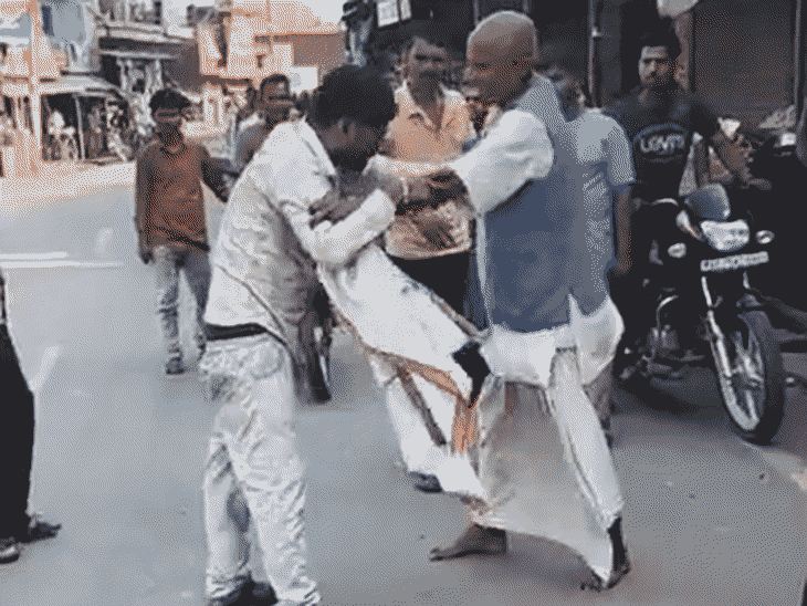 पैसे के लिए ऑटो चालक से लड़ता व्यक्ति।