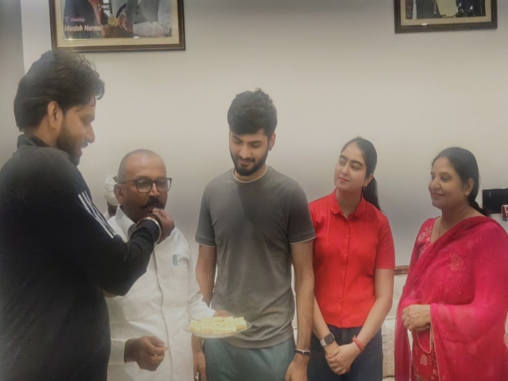मनीष को पदक मिलने पर मिठाई खिलाते हुए परिवार के लोग