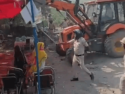 जेसीबी की मदद से टेंट हटवाते पुलिसकर्मी।