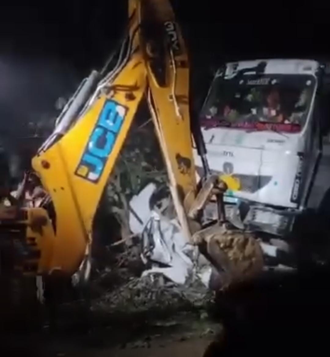 ट्रॉले के नीचे से कार को निकालती जेसीबी।